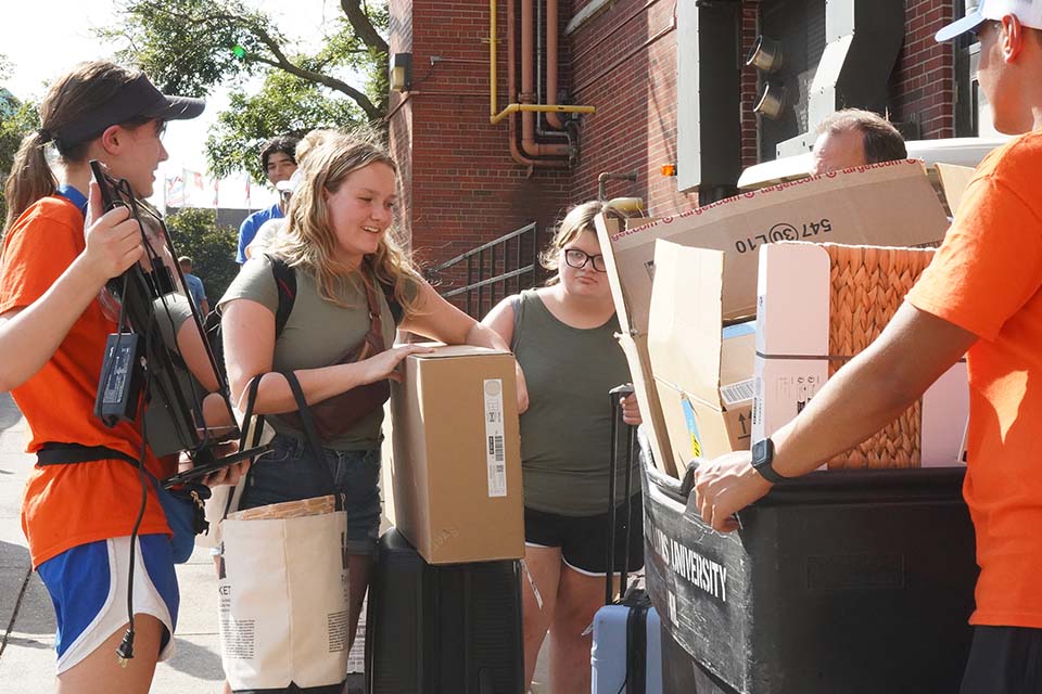 Students help a first-year student carry things to a residence hall.