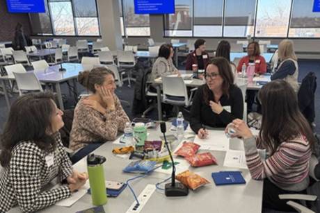 A group of people sit around a table conversing.